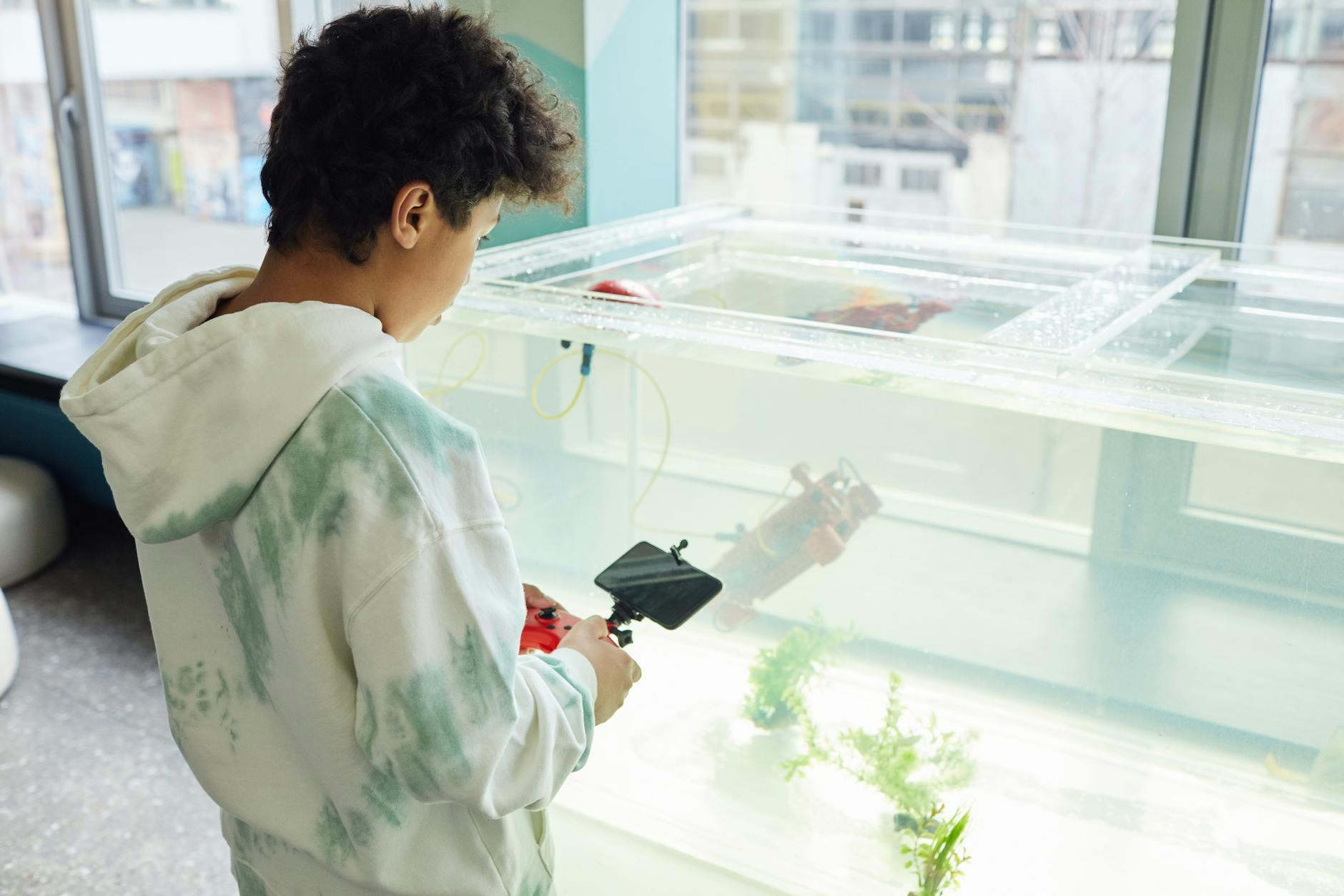 Chłopiec obsługuje zdalne sterowanie przy domowym akwarium