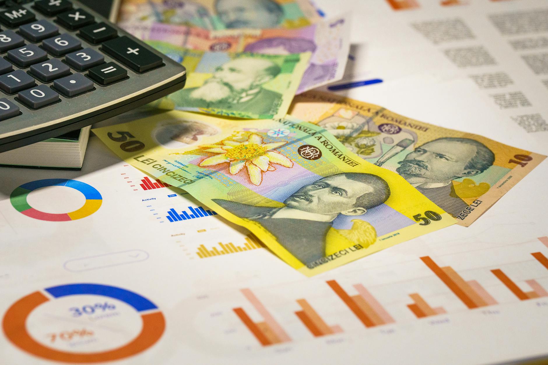 Banknoty i kalkulator obok wykresów symbolizujące obliczenia akwaryjne