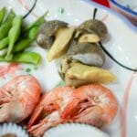 Czy preparaty typu „klarownik” są bezpieczne dla krewetek i ślimaków? Talerz z krewetkami, ślimakami i edamame na dekoracyjnej zastawie